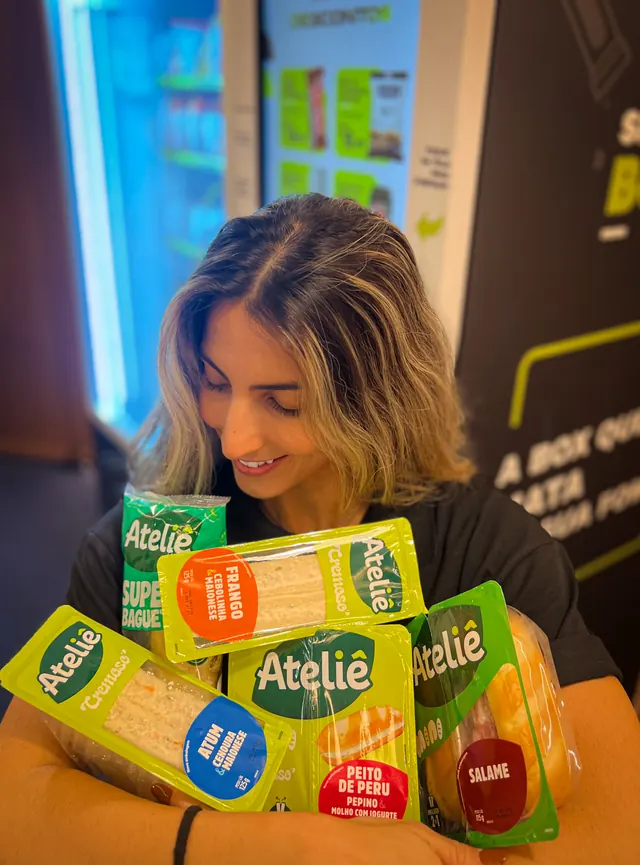 Colaboradora da SmartBox segurando sanduíches e lanches selecionados