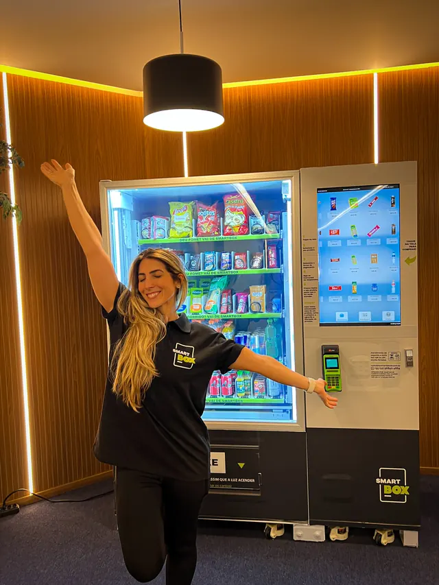 Colaboradora comemorando ao lado da vending machine