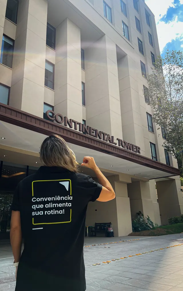 Colaboradora com a camiseta 'Conveniência que alimenta sua rotina' em frente à Torre Continental