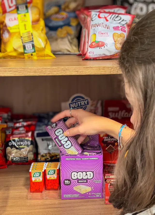 Cliente pegando uma barra de proteína no minimercado