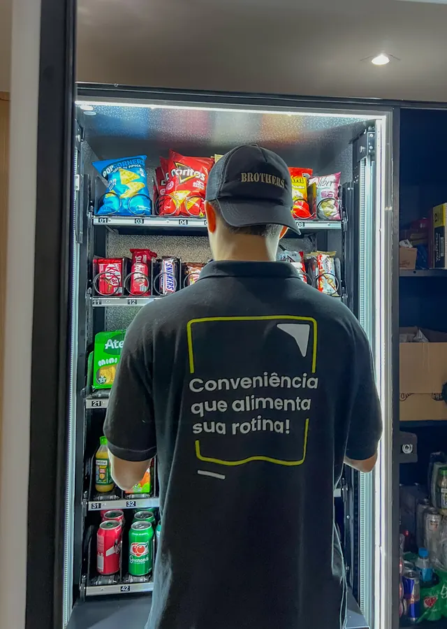 Colaborador da SmartBox abastecendo a máquina, com a frase 'Conveniência que alimenta sua rotina' na camiseta