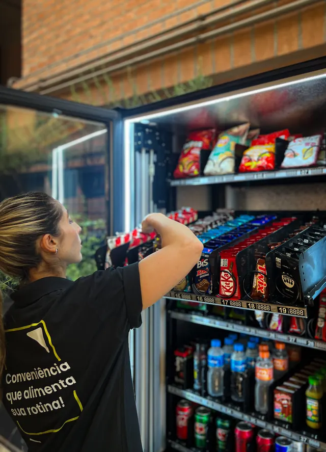 Colaboradora repondo produtos na vending machine